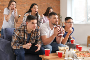 Group of fans watching football on TV and eating tooth friendly snacks.