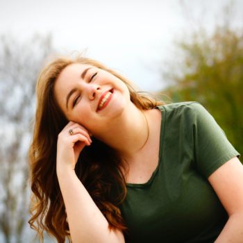 Woman smiling in the sun. Learn if the sun helps whiten your teeth
