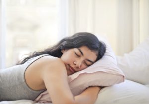 Woman sleeping with pillow. Learn how mouth breathing affects your health. 