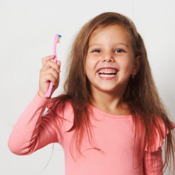 Little girl brushing her teeth on white background. Healthy dental concept