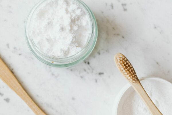 Baking soda in a bowl next to three toothbrushes.