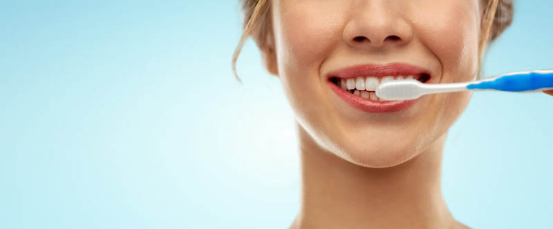 close up of woman with toothbrush cleaning teeth