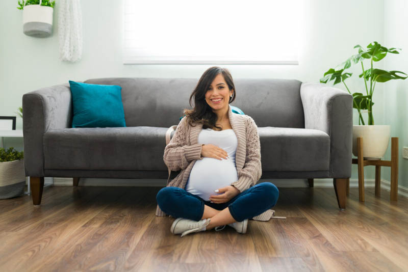 Beautiful pregnant woman posing at home and showing her round belly